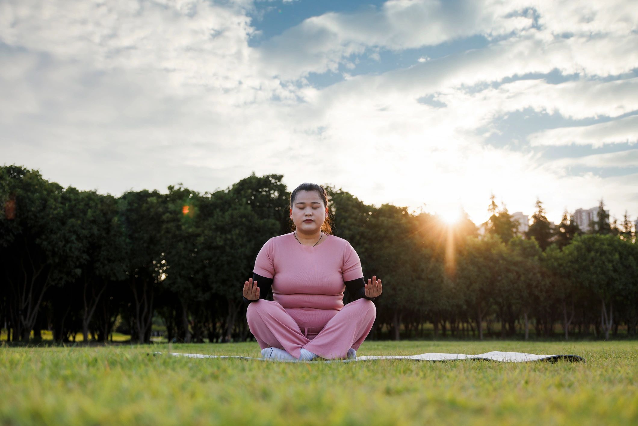 Woman meditating outdoors on a yoga mat